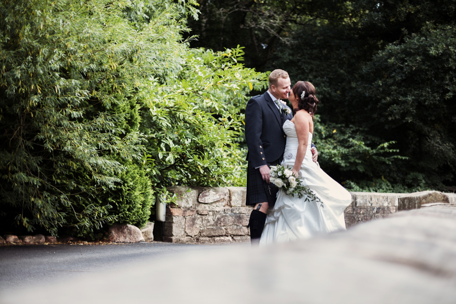Bride and groom kissing on the bridge on the grounds of Dalhousie Castle