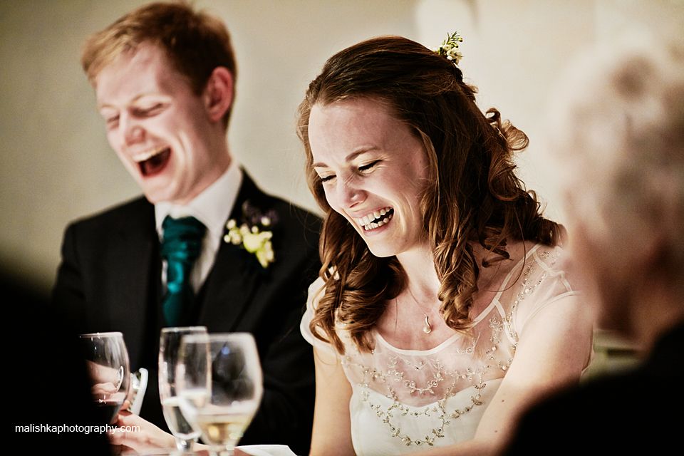 Bride and groom laughing during best man speech