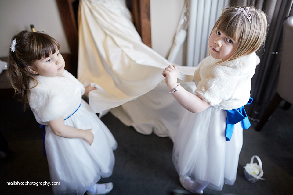 Little bridesmaids helping the bride with her dress