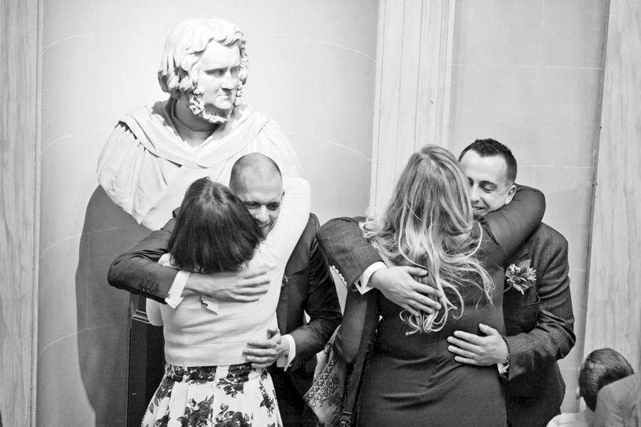 Guests hugging the grooms at civil partnership at Royal College of Physicians in Edinburgh
