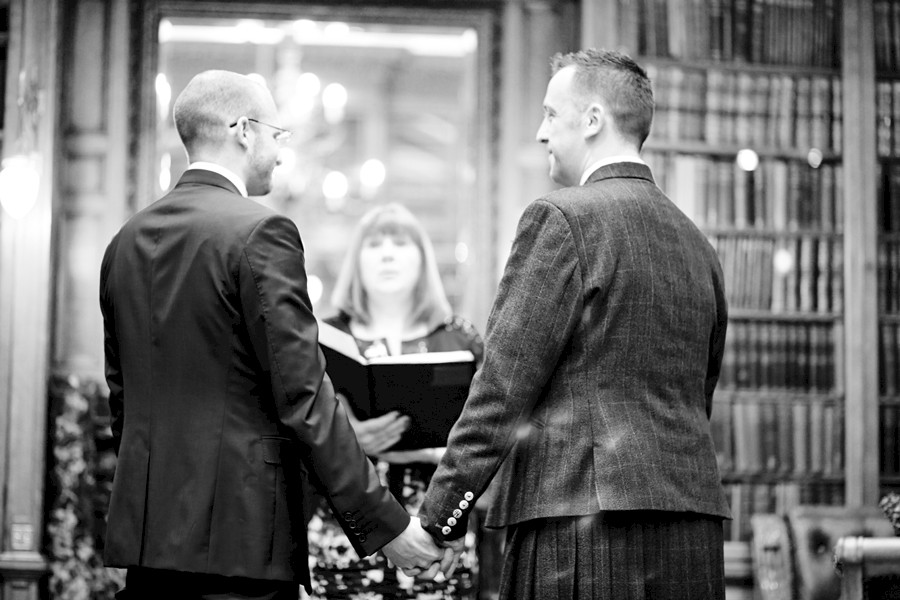 Partners holding hands during civil partnership at Royal College of Physicians in Edinburgh