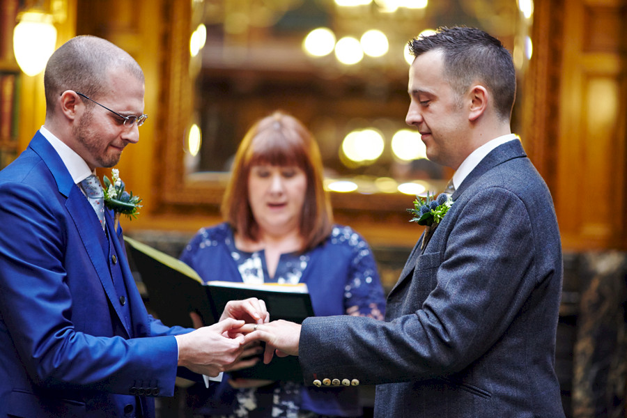 Partners exchanging rings during civil partnership ceremony at Royal College of Physicians in Edinburgh