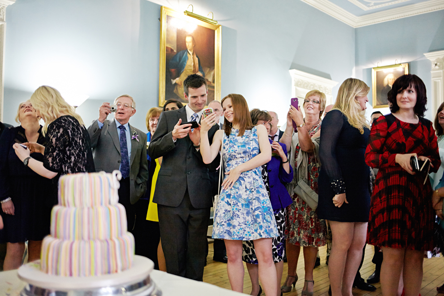 Guests photographing the cake during the wedding ceremony at Royal College of Physicians in Edinburgh